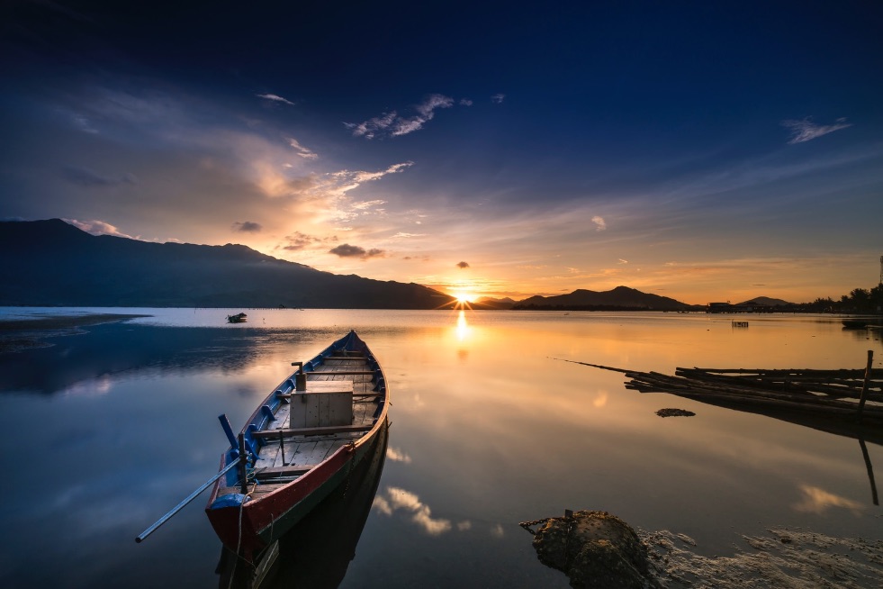 Image of a tranquil lake at sunset with a kayak, symbolizing the start of a journey as a provider offering daily activities.